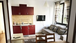 A compact living space with a kitchenette, a dining area, and a sofa by a window.