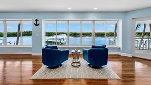 A spacious room with large windows offering a view of a waterway and boats.