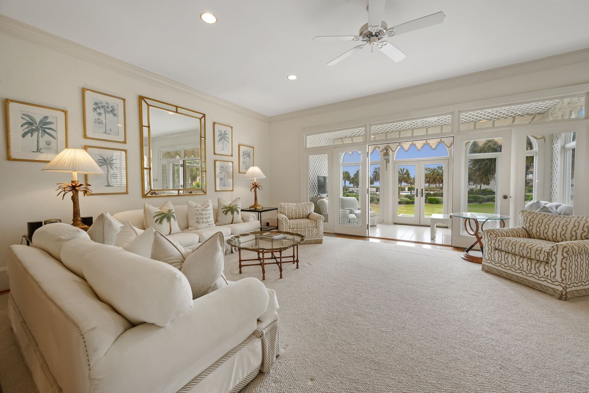 A spacious living room with a high ceiling, large windows, and a view of the outdoors.