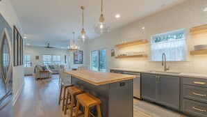Una cocina moderna con una isla central, taburetes de madera e iluminación colgante.