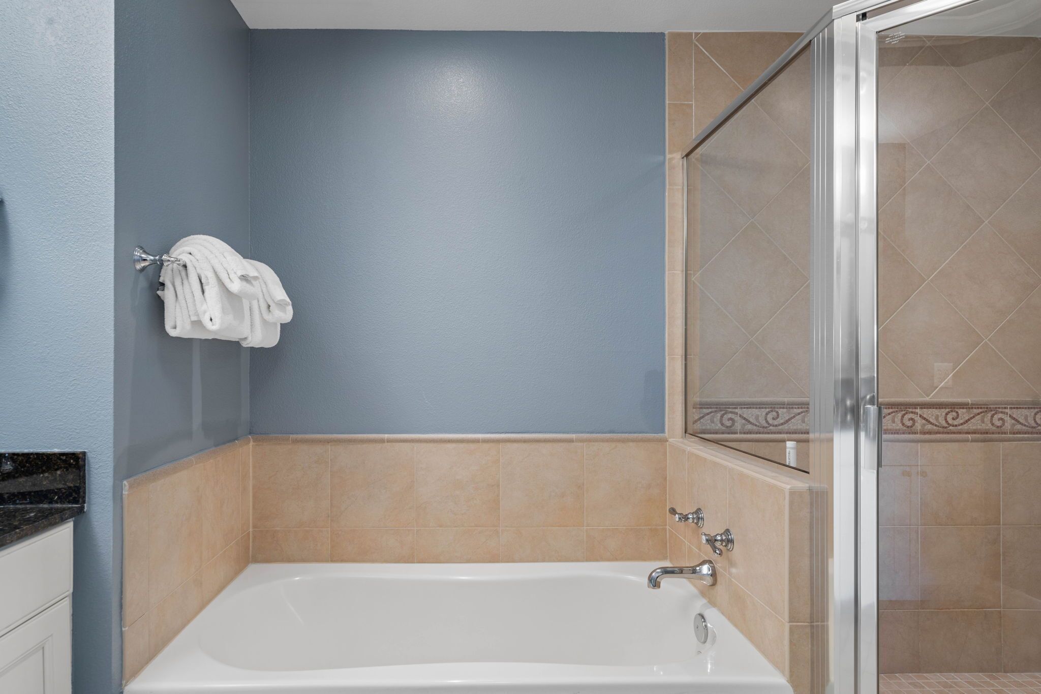 Un bagno con una vasca, una zona doccia e un portasciugamani con asciugamani.