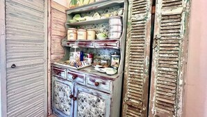 A vintage cabinet with multiple compartments, some labeled with items like coffee and rice.