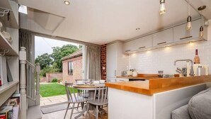 A modern kitchen with a wooden island, white cabinets, and pendant lighting.