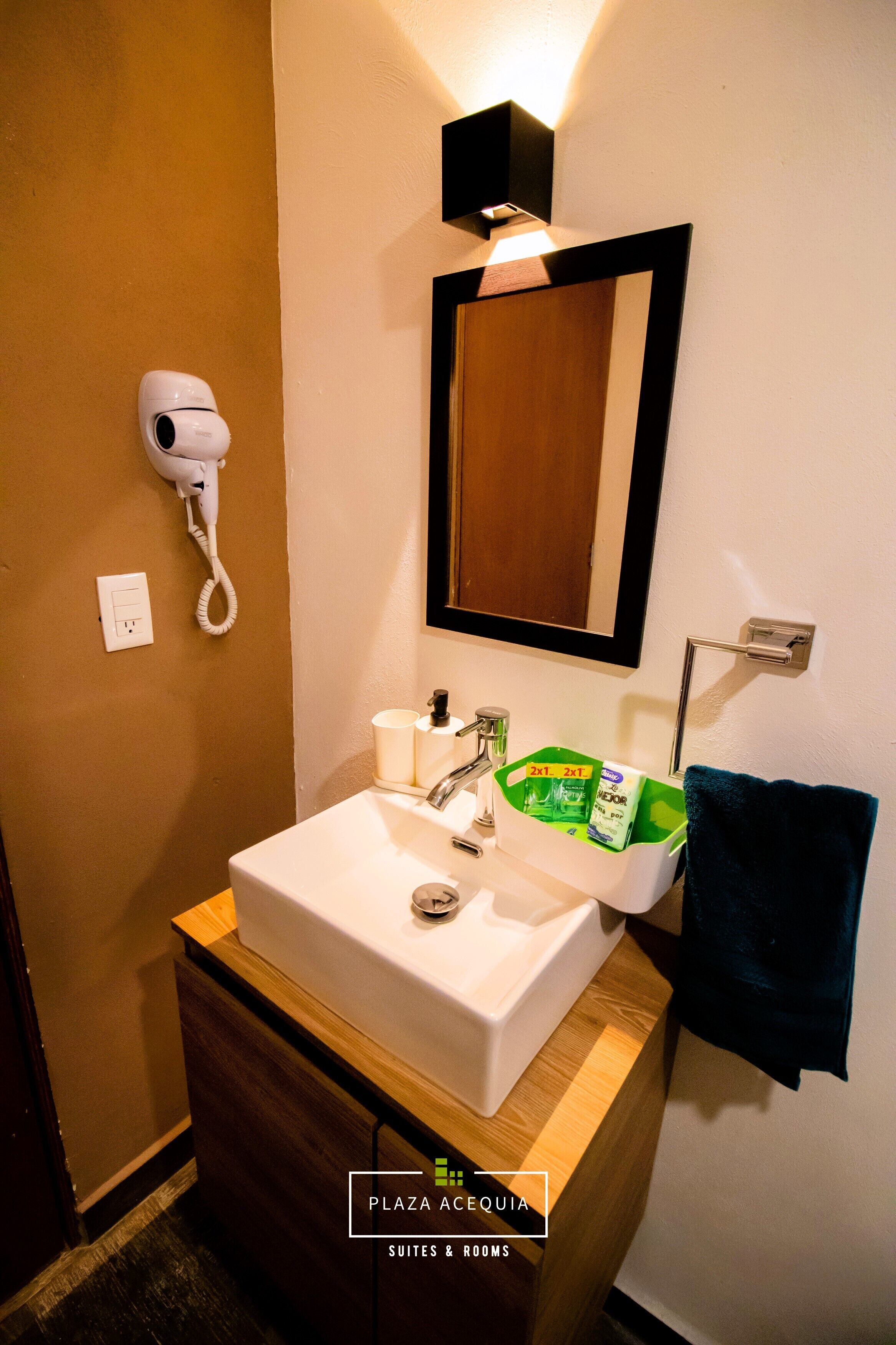 Un baño con lavamanos blanco, un secador de pelo, un espejo y un perchero para toallas.