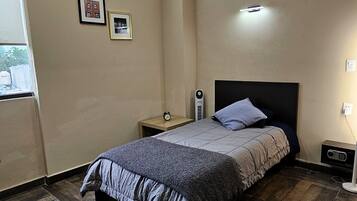A bedroom with a bed, nightstands, a heater, and a window.