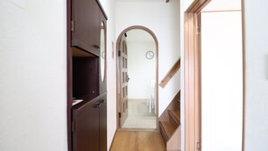 A narrow hallway with wooden doors, a staircase, and a white wall with clocks. - Tsuruhashi East III (Osaka)