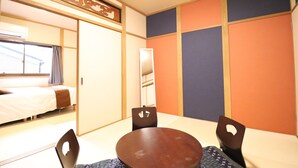 A room with a bed, a table with chairs, and a sliding door. - Tsuruhashi East III (Osaka)