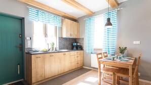 A kitchen with wooden cabinets, a sink, and a dining area with a table and chairs. - Beach front home in Nowecin with sauna (Nowecin)