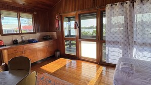L’intérieur d’un chalet en bois comprend une cuisine, un coin repas et un lit.