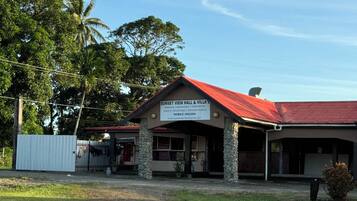 A building with a red roof and a sign indicating it is Sunset View Hall & Villa's, offering services like weddings, anniversaries, and birthday parties.