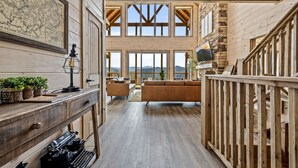 Amplio espacio tipo loft con techos altos, ventanas grandes, un escritorio de madera y una zona de estar acogedora.