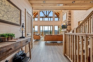 Un interior espacioso con paredes de madera, un escritorio con máquina de escribir, un mapa y vistas al exterior.