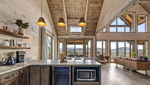 Una cocina amplia con microondas integrado, armarios de madera y luces colgantes.