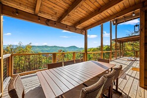 A wooden deck with a table and chairs, overlooking a mountainous landscape. - Mountain Views, Barrel Sauna, Hot Tub, 3 King Suites, Game Room, Pool (Sevierville)