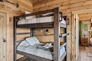 Una cama individual con estructura de madera, una mesita de noche pequeña y una puerta con manija.