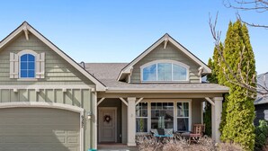 A two-story house with a garage, a front porch, and a large window. - Spacious Modern Home—Fire Pit, Basketball Hoop, Pop-A-Shot & Kids' Toys for Family Fun! (Coeur D Alene)
