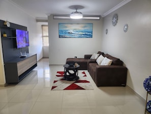 Una sala de estar con un sofá, una mesa de centro, un televisor y un cuadro en la pared.