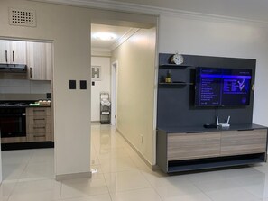 Una cocina moderna con horno integrado, un comedor con mesa y una sala de estar con televisor de pantalla plana.