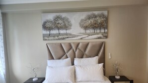 A bedroom with a bed, two nightstands, a painting, and a window with a curtain. - A Two-bedroom Holiday Apartment, at the Heart of South Beach Durban (Durban)