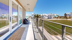 A balcony with a view of houses and a grassy area. - Resort Style Pools, Boardwalk to the Beach (Port Aransas)