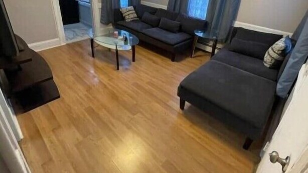 Uma sala de estar com sofá, mesa de centro e ventilador de teto.