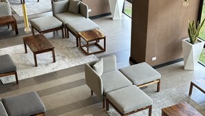 A modern lounge area with sofas, armchairs, and wooden tables arranged on a patterned carpet. - Located in Zona 11, centrally-located,  family friendly, near airport, near mall (Guatemala City)
