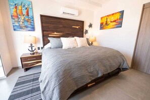 Une chambre à coucher avec un lit, des tables de chevet, une tête de lit en bois et des œuvres d’art accrochées aux murs.