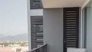 Un balcón con una silla y vistas a un paisaje urbano.