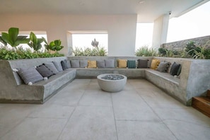 A modern outdoor seating area with a concrete bench and a central fire feature.
