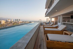 Une piscine sur le toit, dotée de chaises longues et offrant une vue sur la ville.