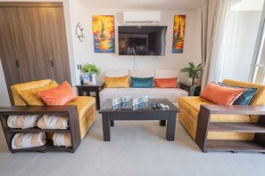 Un salon moderne avec un ensemble de canapés, une table basse et un téléviseur à écran plat.