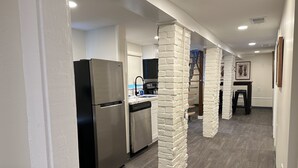 Una cucina moderna con frigorifero in acciaio inossidabile, lavastoviglie e parete decorata con mattoni bianchi.