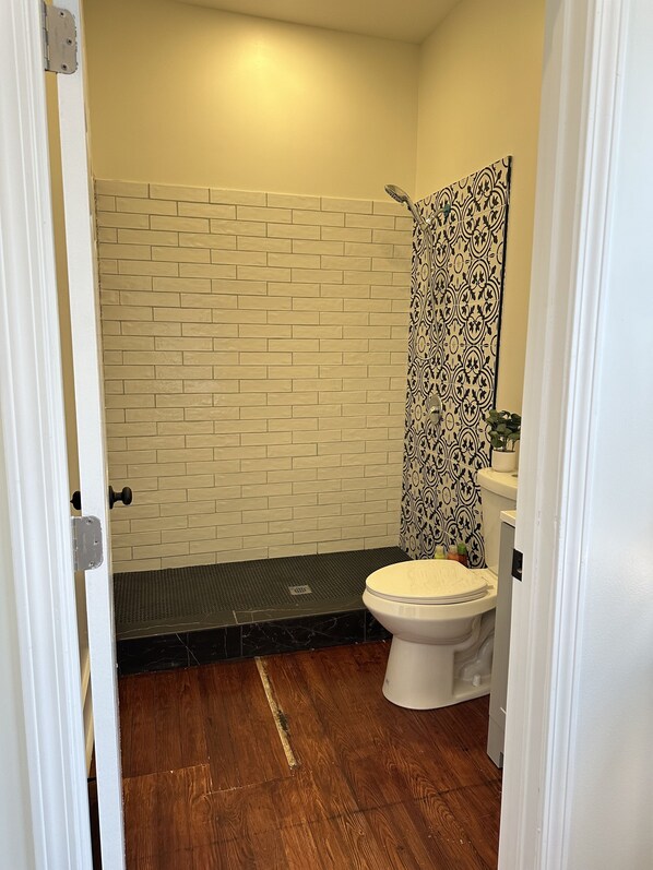 Een badkamer met een metselwerk-achtergrond, een douche met gordijn en een toilet.