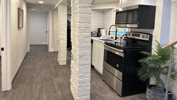 Una cucina moderna con mobili bianchi, un piano cottura nero e un forno a microonde.