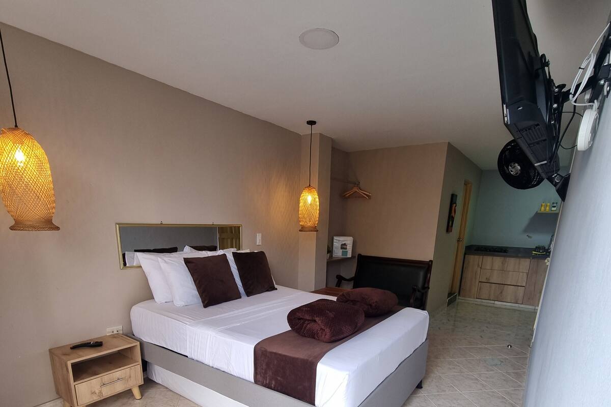 A bedroom with a bed, bedside table, and a hanging light fixture.