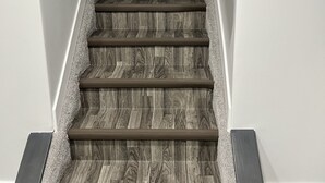 Un escalier avec des marches en bois et une rampe, menant à un palier.