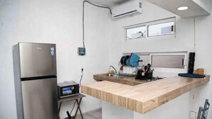 Una cocina compacta con un refrigerador de acero inoxidable, un lavamanos pequeño y una encimera de madera.
