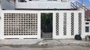 Un edificio blanco con una entrada protegida por un portón y una pequeña ventana.
