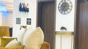 A living room with a sofa, a clock, a wine rack, and a decorative bull statue. - 2 Bed Apartment Sleeps 4 - Pool - Free Parking (Lekki 1)
