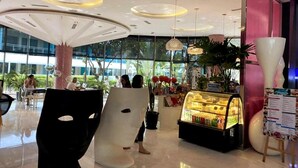 Un espacio interior moderno con una zona de estar central, una exhibición de alimentos y un ventanal que ofrece vistas al exterior.