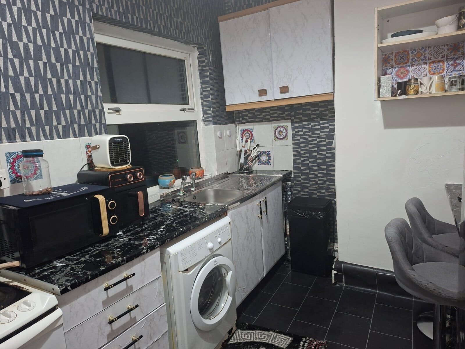 A compact kitchen with a washing machine, a sink, and a window.