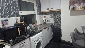 A compact kitchen with a washing machine, a sink, and a window.
