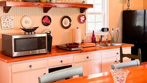 A kitchen with a microwave, stove, sink, and various dishes on the wall.
