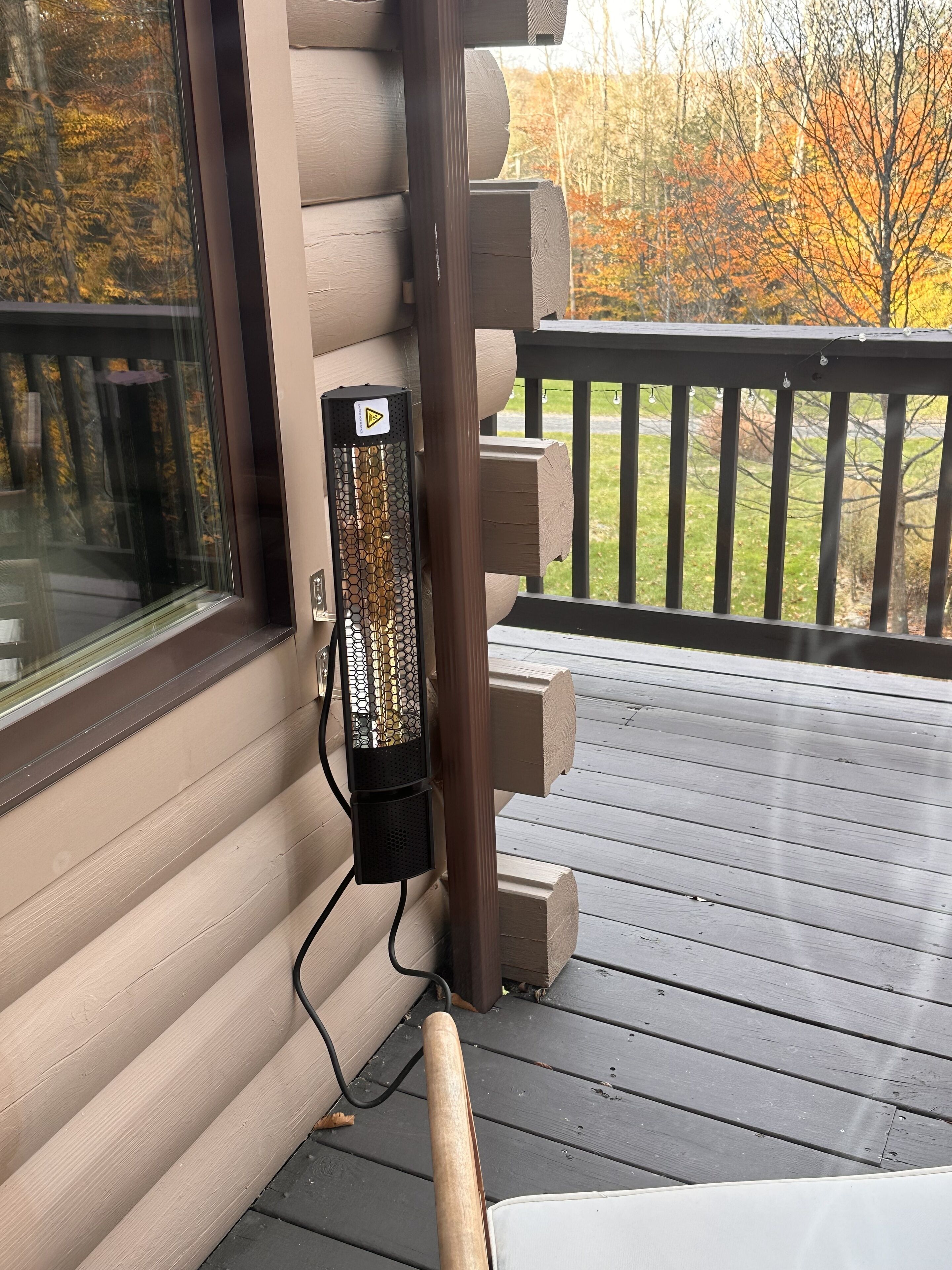 A wooden deck with a glass door and a wall-mounted heater.
