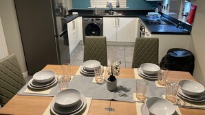 A modern kitchen with a dining area set for four. - MK439FJ Sleeps 7 with Pet Friendly Garden (Bedford)
