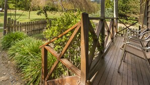 A wooden deck with wicker chairs and a view of a landscaped garden.