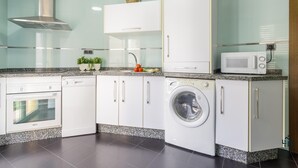 A modern kitchen with white cabinets, a built-in washing machine, a microwave, and a dishwasher.