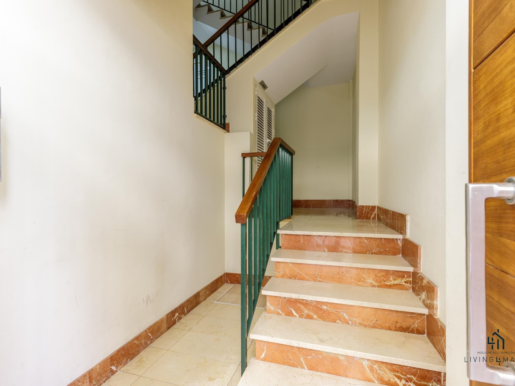 A staircase with marble steps and a wooden handrail, leading to an upper floor.