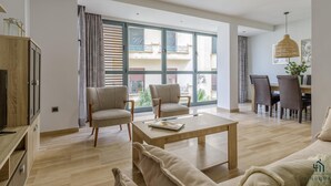 A spacious living room with a large window, a wooden coffee table, and a sofa.