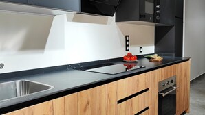 Een moderne keuken met een zwart aanrecht, houten kastjes en roestvrijstalen apparatuur.
